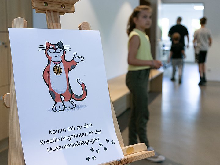 Ein Aufsteller mit Abteikater Theophil weist zu den Kreativ-Angeboten der Museumspädagogik