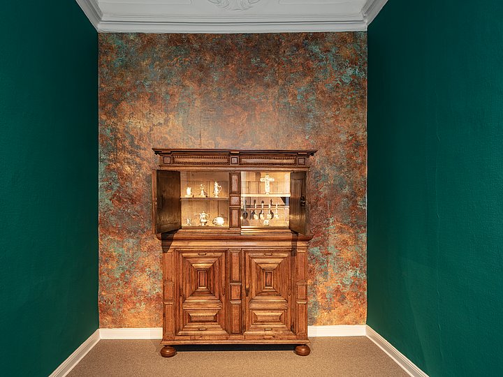 Barocker Schrank vor einer grünen Wand mit gemustertem Feld