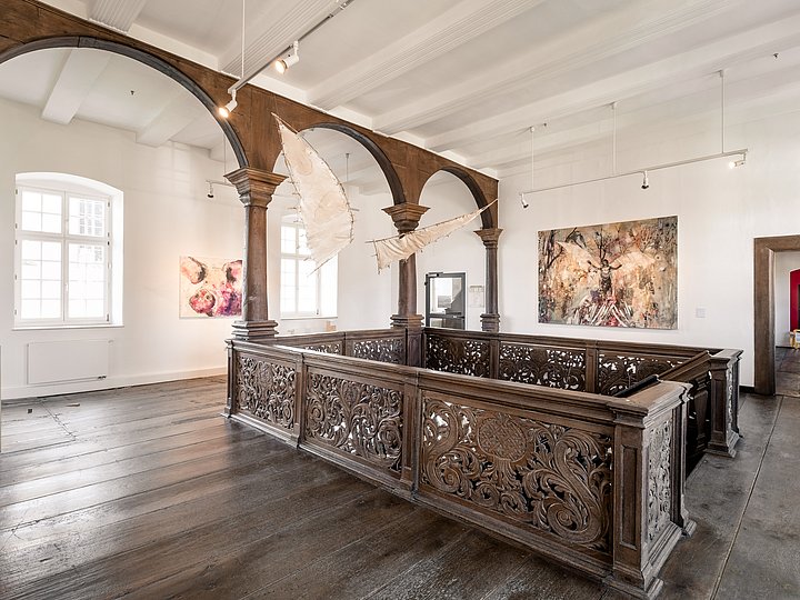 Saal mit Arkaden und geschnitzter hölzerner Empore