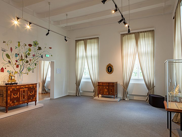 Raum zur Wohnkultur mit Kommode, Vitrine und einem Baummotiv an der Wand