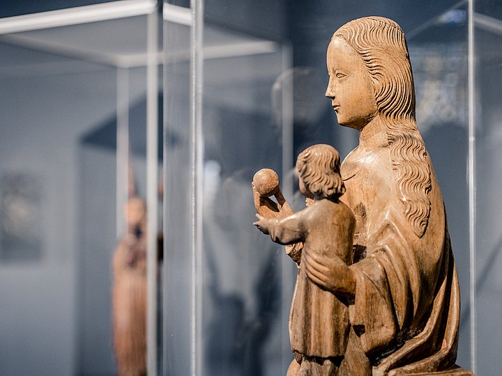 Holzfigur einer Madonna mit Kind hinter Glas